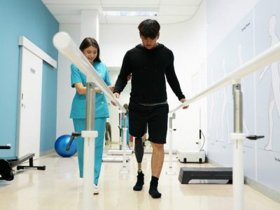 Nurse helping a man with a prosthetic leg walk